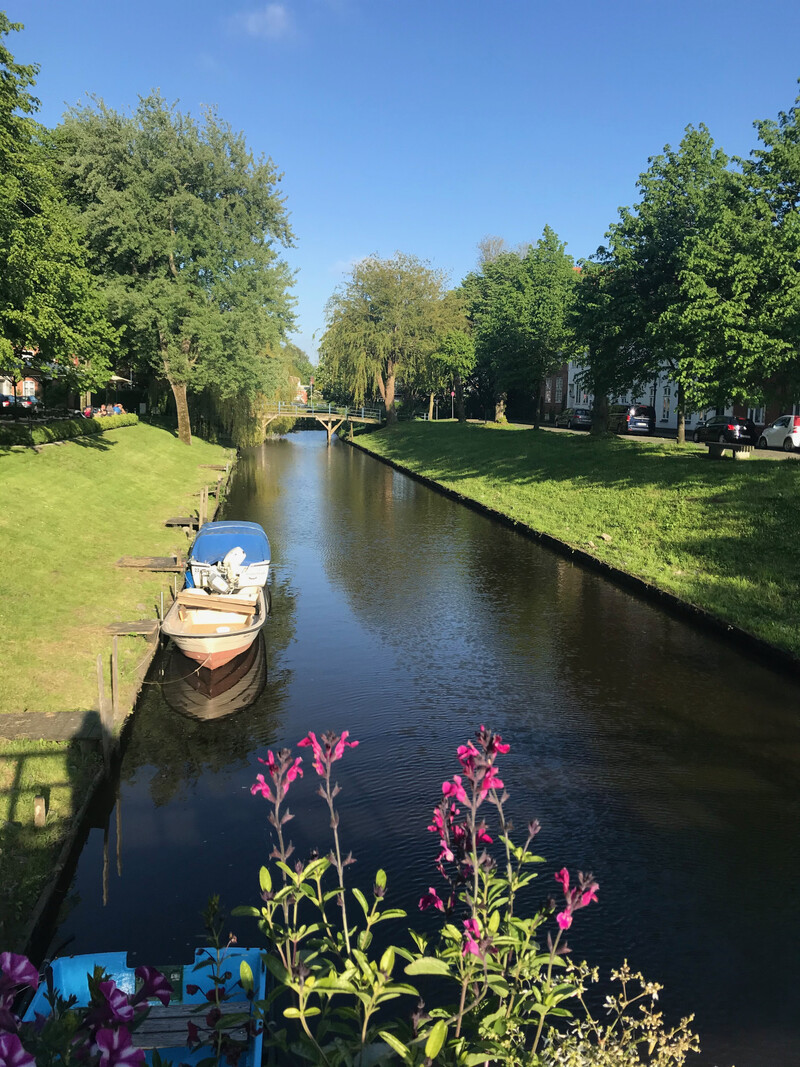 Gracht in Friedrichstadt mit vertäutem Boot und Blumen