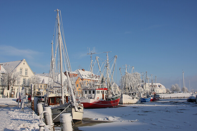 Verschneiter Hafen mit vereisten Krabbenkuttern im Winter