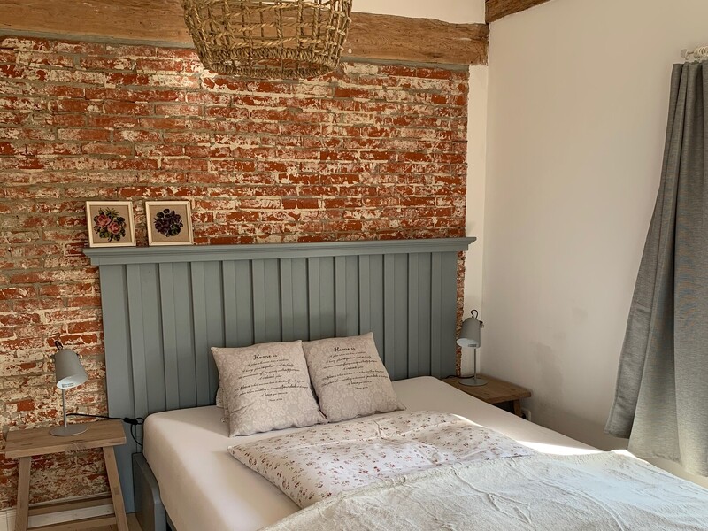 Schlafzimmer einer Ferienunterkunft mit Doppelbett, Backsteinwand und Holzbalken