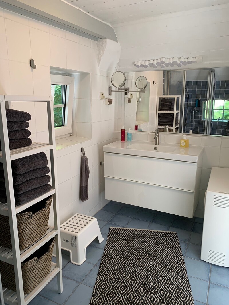 Badezimmer einer Ferienunterkunft mit Waschtisch, großem Spiegel, Handtuchregal und Dusche