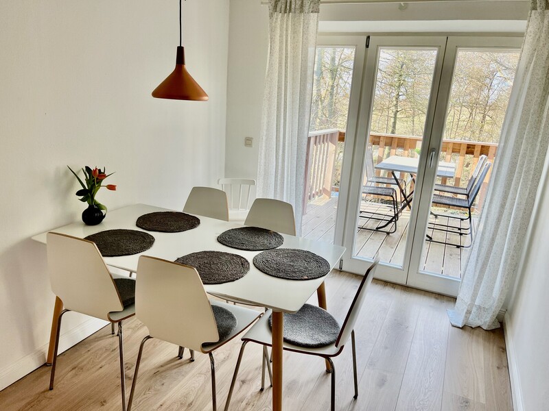 Heller Essbereich mit weißem Esstisch für sechs Personen und Balkontür mit Blick auf Balkon und Bäume