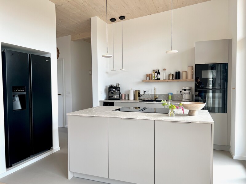Alt-Text: Moderne offene Küche mit Kücheninsel und Marmorarbeitsplatte, Ceranfeld, Side-by-Side-Kühlschrank, Einbaugeräten und Pendelleuchten