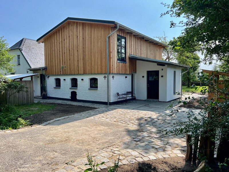 Kernsaniertes Ferienhaus mit weißer Fassade und Holzverkleidung