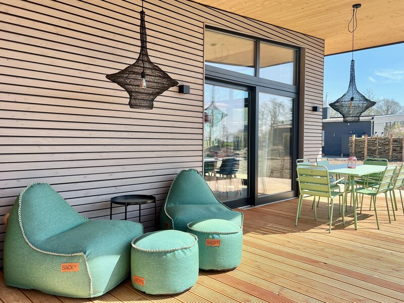 Überdachte Holzterrasse vom Haus NordseeGut mit türkisen Sitzsäcken und mintgrünen Möbeln in der Sonne