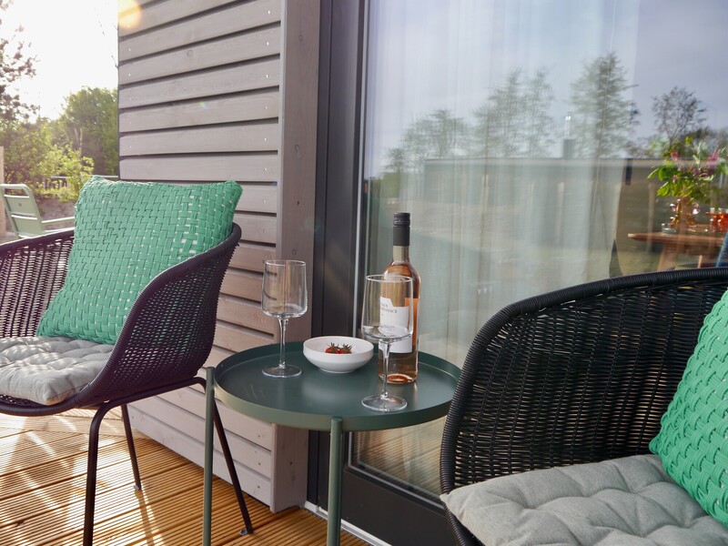 Terrassenecke vom Haus NordseeGut mit Rattansesseln, Beistelltisch, Wein und Erdbeeren in der Abendsonne