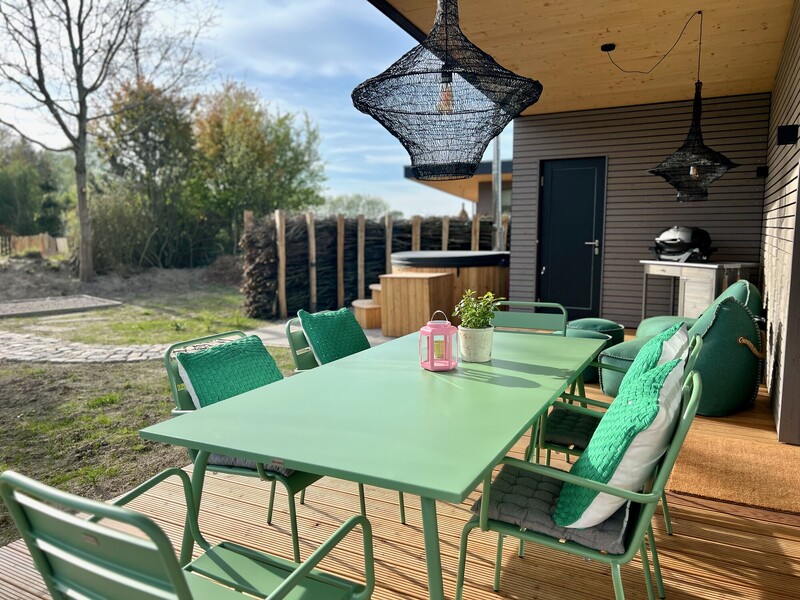 Überdachte Terrasse vom Haus NordseeGut mit mintgrünem Esstisch, Grill und Badebottich im Garten