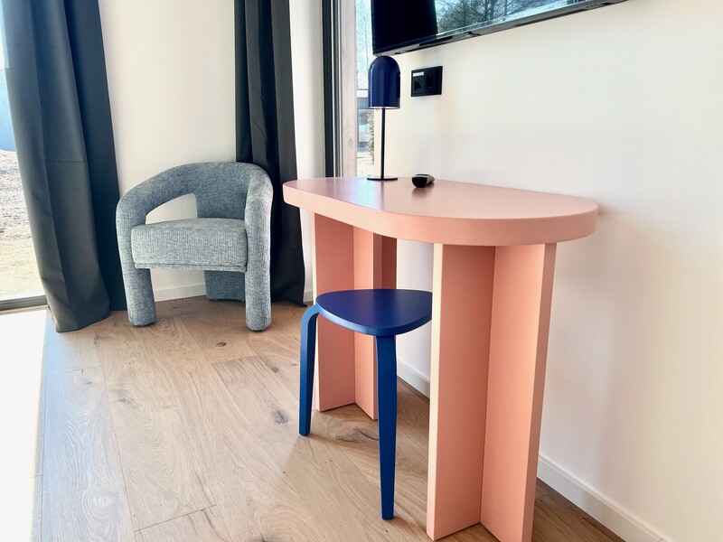 Sitzecke im Haus NordseeGut mit rosa Konsolentisch, blauem Hocker, grauem Sessel und Tischleuchte