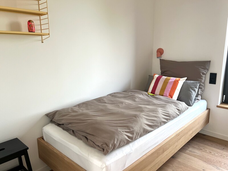 Schlafzimmer im Haus NordseeGut mit Einzelbett aus Holz, Wandregal und Wandleuchte