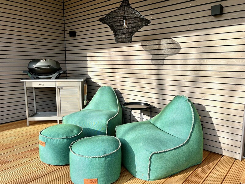 Lounge-Ecke auf der Terrasse vom Haus NordseeGut mit türkisen Sitzsäcken, Hockern und Grill