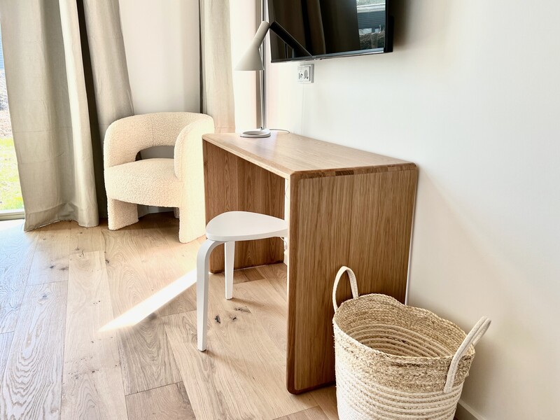 Sitzecke im Haus NordseeLuft mit Holz-Konsolentisch, weißem Hocker, Bouclé-Sessel und Tischleuchte