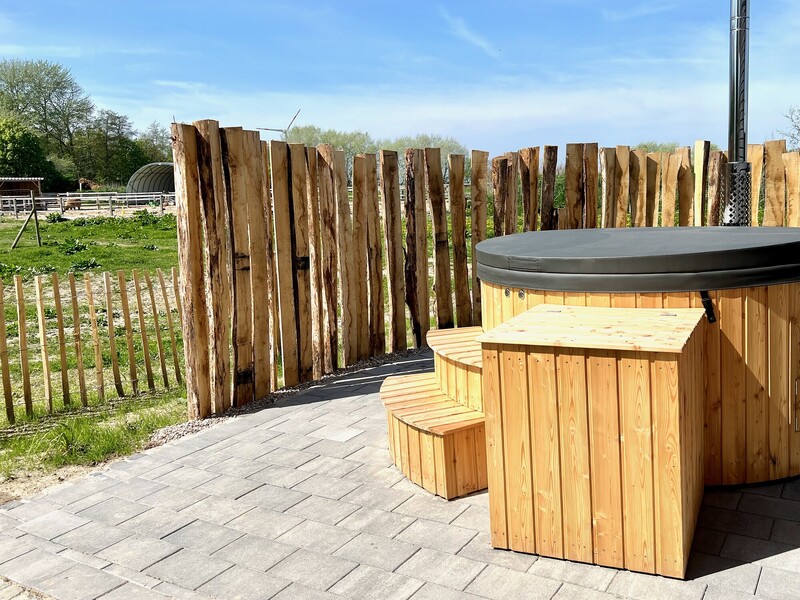 Hölzerner Badebottich mit Ofen und Sichtschutz auf der Terrasse vom Haus NordseeLuft mit Feldblick