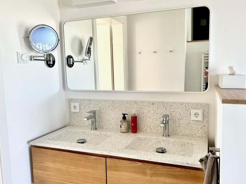 Waschtisch im Haus NordseeLuft mit hellem Terrazzo-Doppelwaschbecken, großem Spiegel und Holzunterschrank