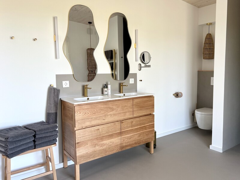 Badezimmer vom Haus NordseeZeit mit Holz-Doppelwaschtisch, geschwungenen Spiegeln und WC