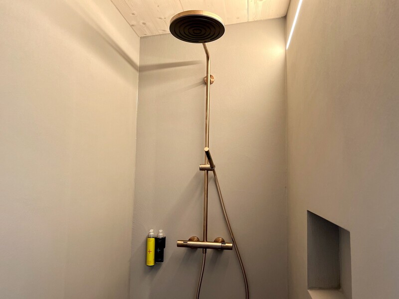 Dusche im Haus NordseeZeit mit goldener Regendusche, fugenlosen Wänden und Wandnische