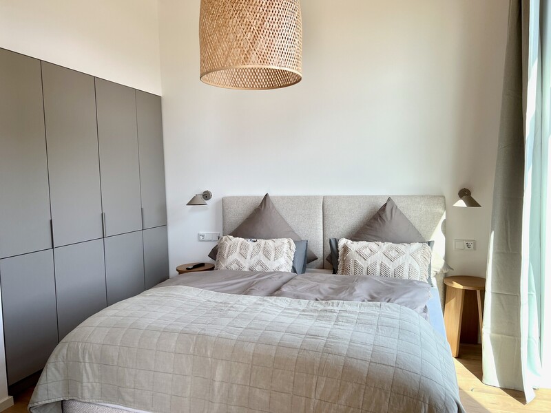 Schlafzimmer im Haus NordseeZeit mit Doppelbett, Kleiderschrank, Rattanleuchte und Wandleuchten