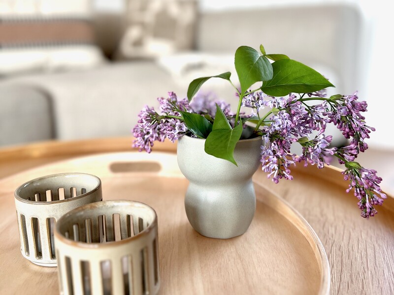 Nahaufnahme aus dem Haus NordseeZeit mit Vase voller Flieder und Kerzenhaltern auf rundem Holztablett