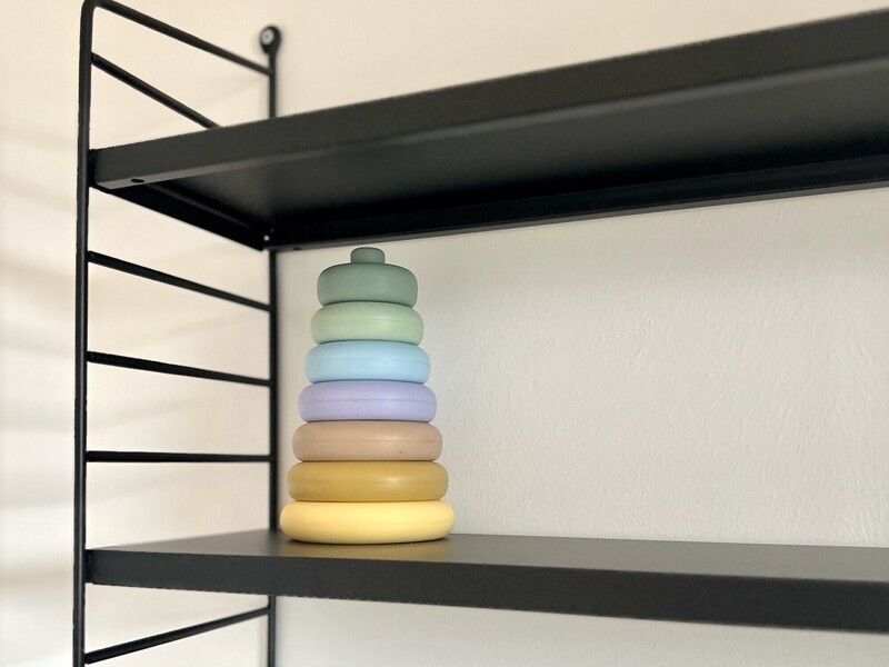 Deko-Detail in StrandHaus: hölzerner Stapelturm als Kinderspielzeug auf einem schwarzen Regal