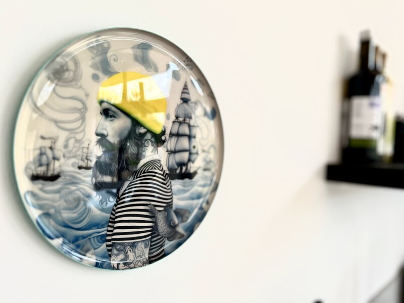 Dekorativer Wandteller mit maritimem Motiv an heller Wand in StrandHaus