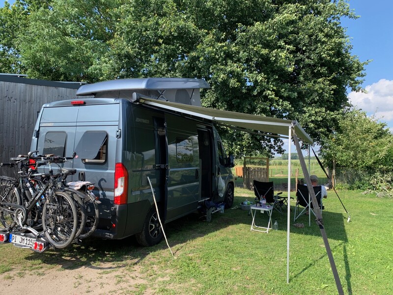 Campingstellplatz mit Wohnmobil und Markise im Grünen