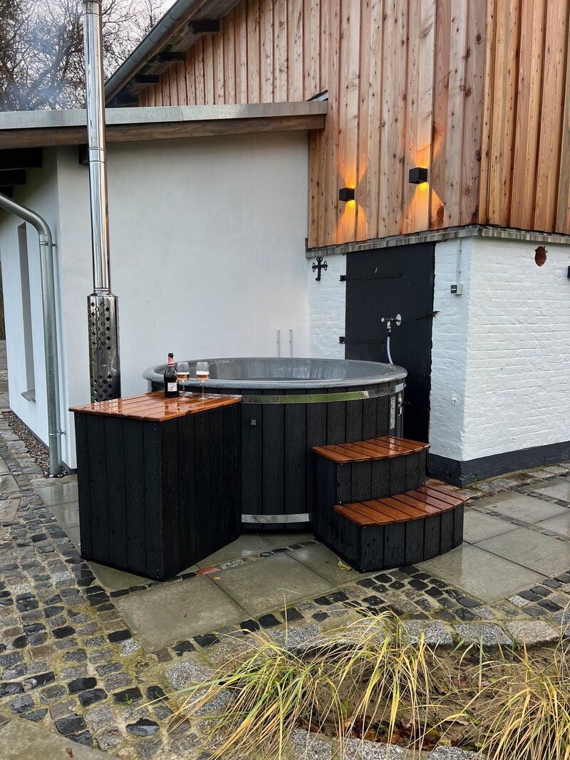Hot Tub mit Holzverkleidung und Treppe an der Terrasse vom Haus Scheune, mit Sektflasche und zwei Gläsern