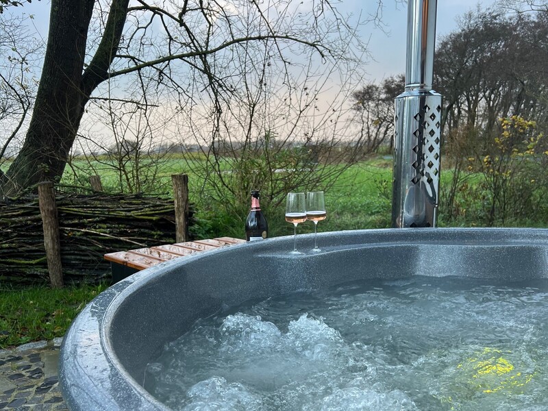 Hot Tub im Garten vom Haus Scheune mit sprudelndem Wasser, Sektflasche, zwei Gläsern und Blick auf die Felder
