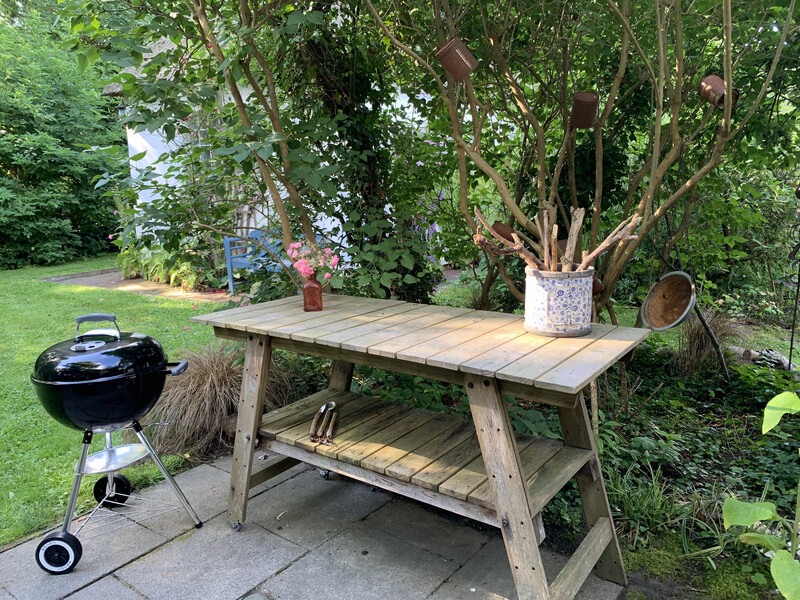 Garten der Reetdachkate 1813 mit Kugelgrill, Holz-Beistelltisch, Terrasse und dichtem Grün